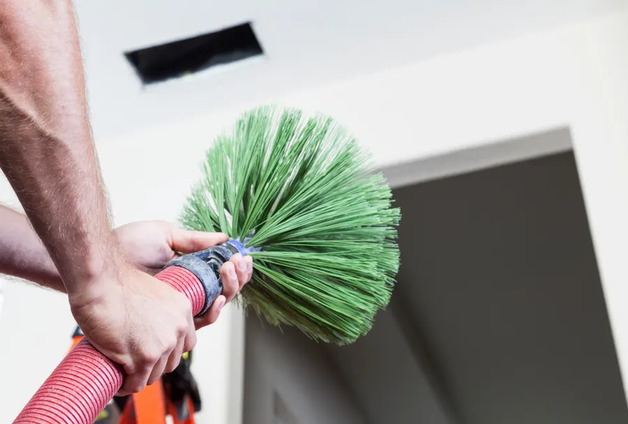 A rotating brush cleaning a ventilation duct