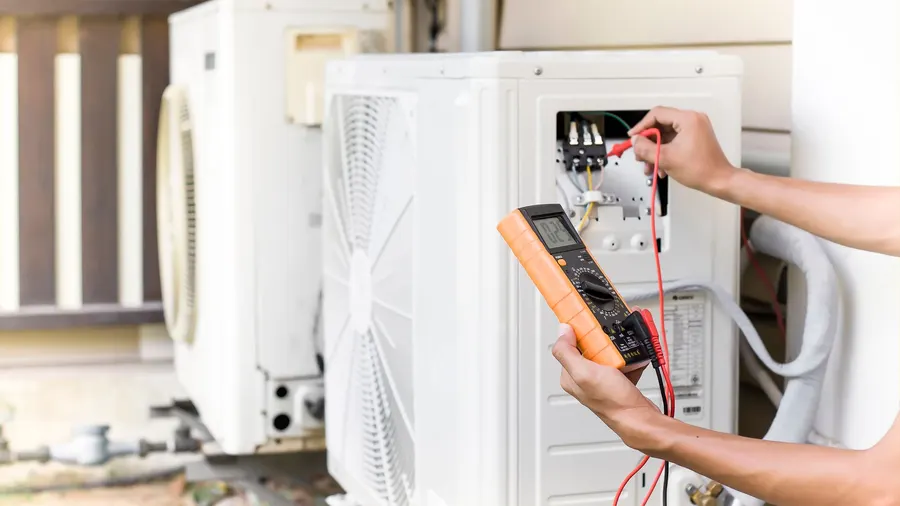 A technician testing an outdoor unit with a meter